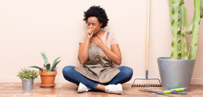 Gardener woman sitting on the floor is suffering with cough and feeling bad