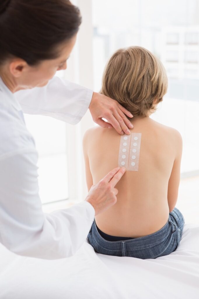 Healthcare provider applying patch test to patient's back