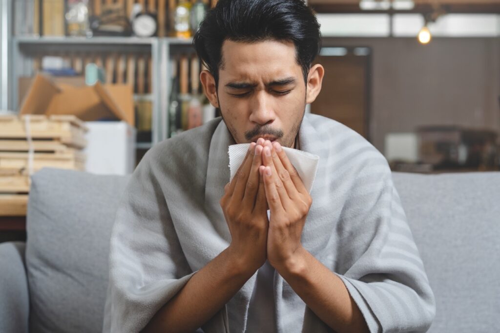 Man sneezing into tissue due to environmental allergens